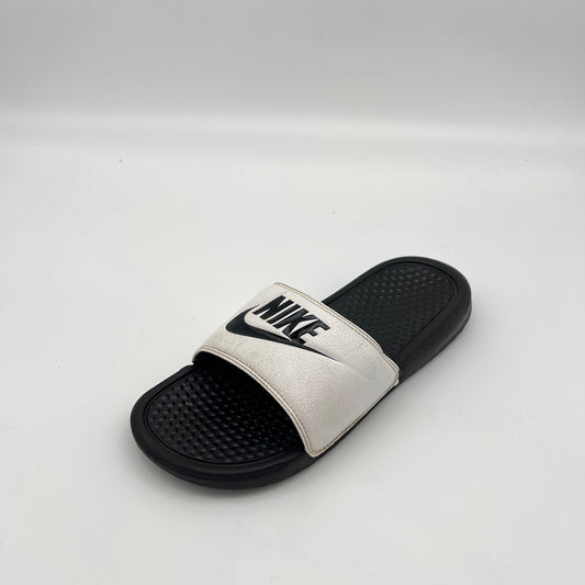 Nike athletic slides featuring a white logo-branded strap and textured black sole.