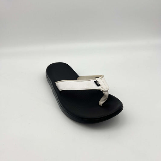 Black sandal with a white strap on a light gray background