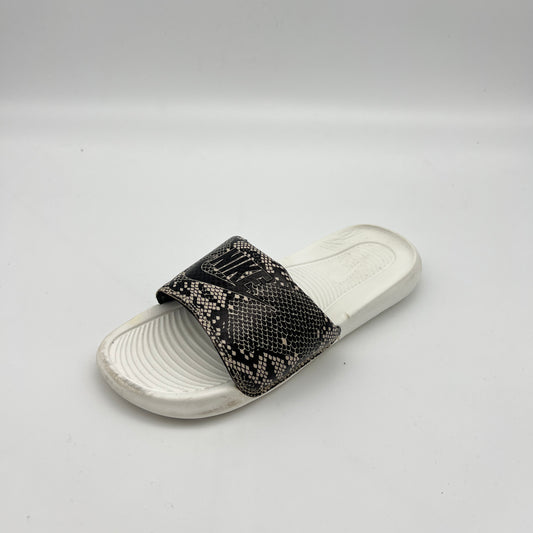 White slide sandal with black patterned strap on a light gray background