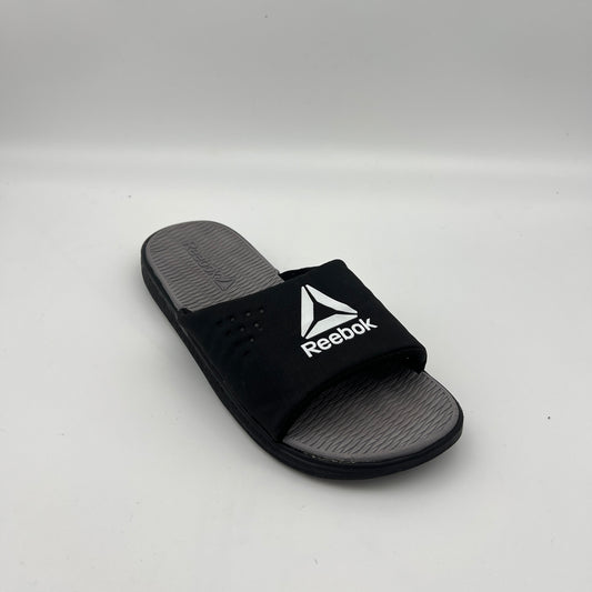 Black Reebok slide sandal on a light gray background