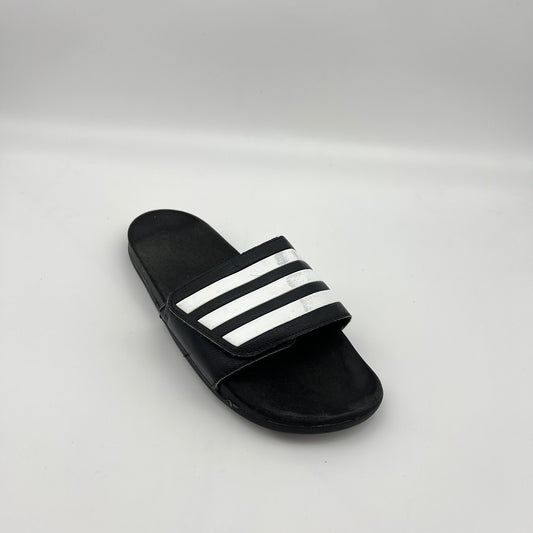 Black slide sandal with white stripes on a light gray background
