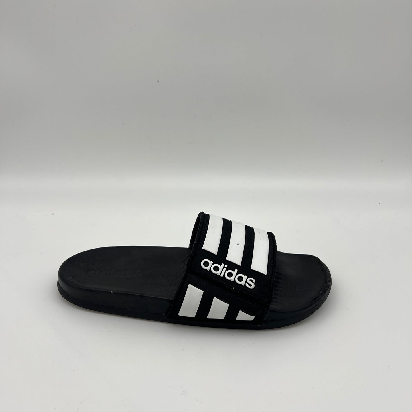 Black and white Adidas Adilette Comfort adjustable slide with three stripes and logo.