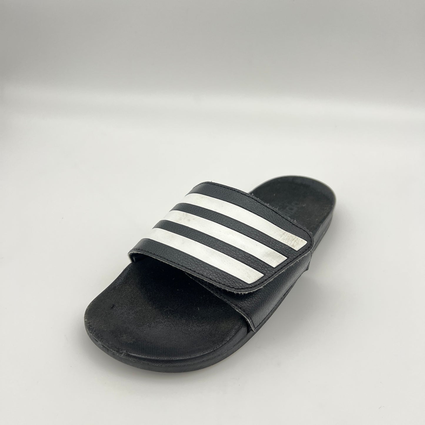 Black slide sandal with white stripes on a light gray background
