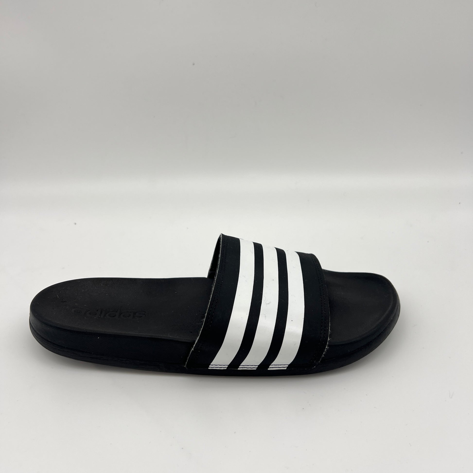 Black Adidas Adilette Comfort slide with three white stripes across the fixed synthetic strap.