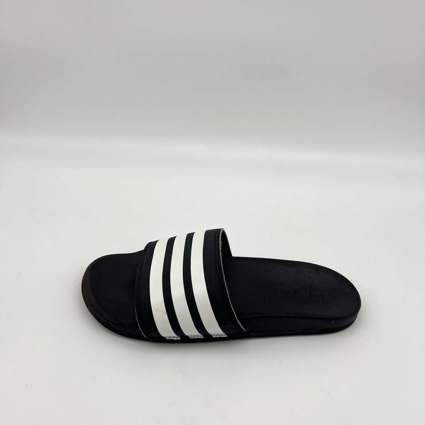 Single black Adidas Adilette Comfort slide with three white stripes on a white background.