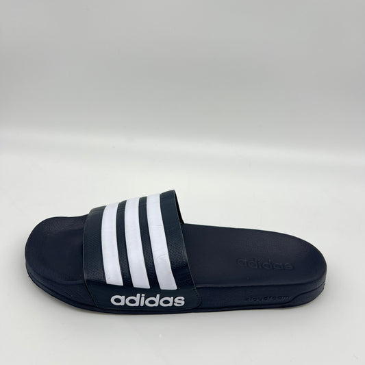 Black Adidas slide sandal with white stripes on a light gray background