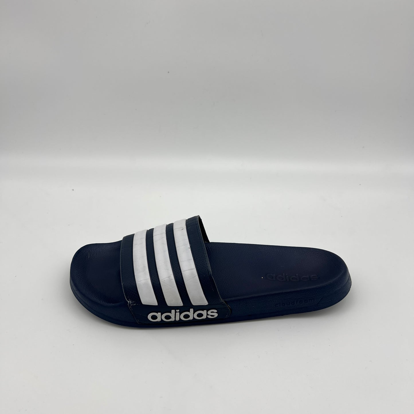 Side profile of navy blue Adidas Adilette Shower slides with white three-stripes and Cloudfoam logo.