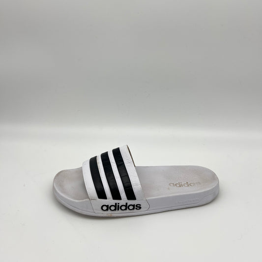 Side view of white Adidas Adilette Shower Slides with black stripes on the strap and a logo on the Cloudfoam midsole.
