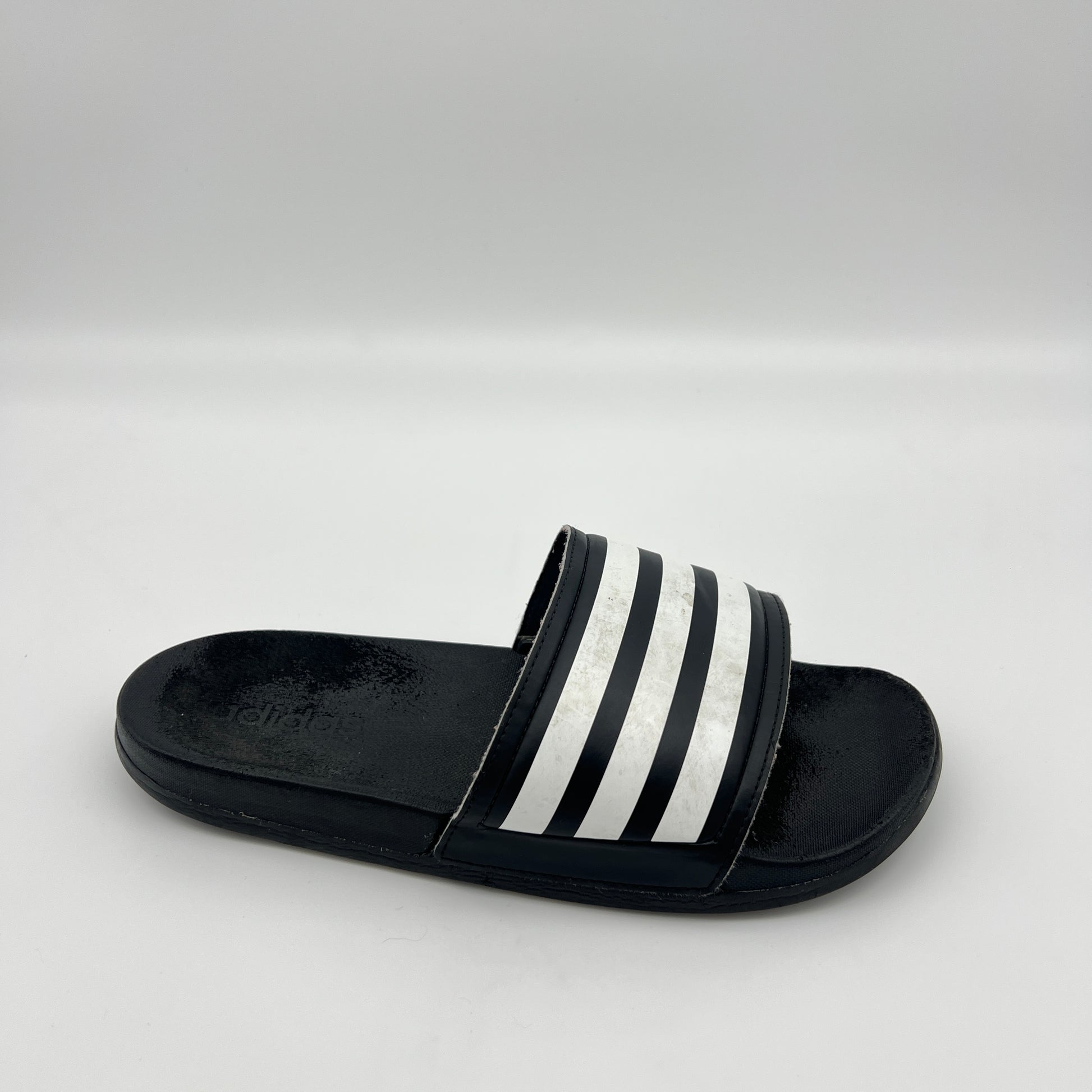 Black slide sandal with white stripes on a light gray background