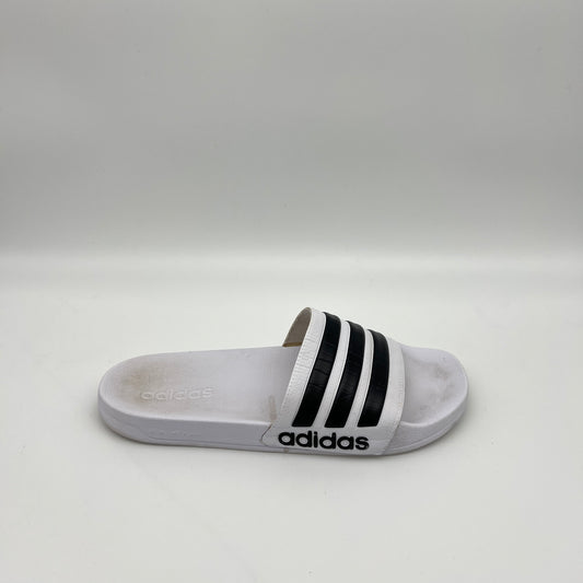 A side profile of a white Adidas Adilette Shower slide with black three-stripes on the strap and a contoured Cloudfoam footbed.