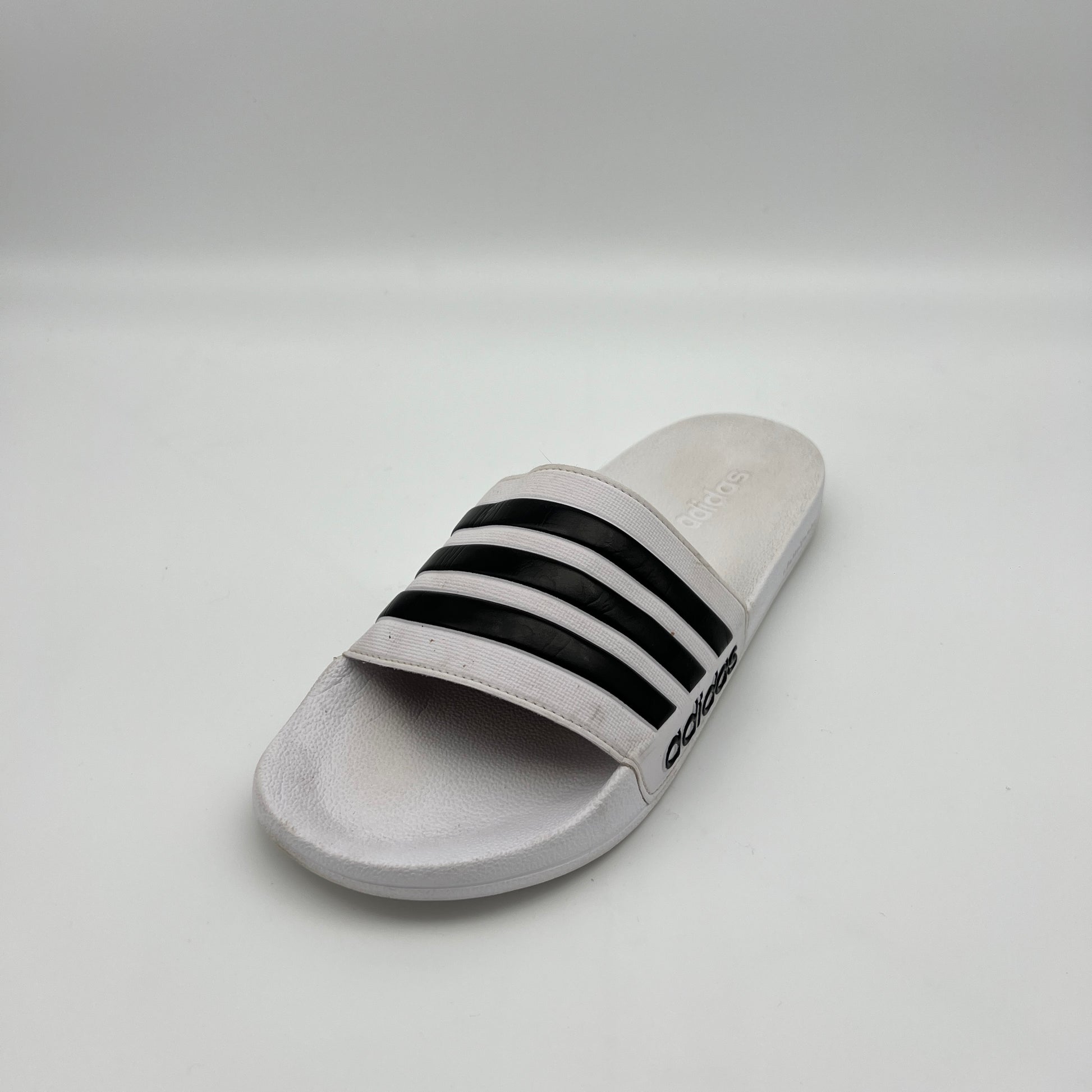 Gray slide sandal with black stripes on a light gray background