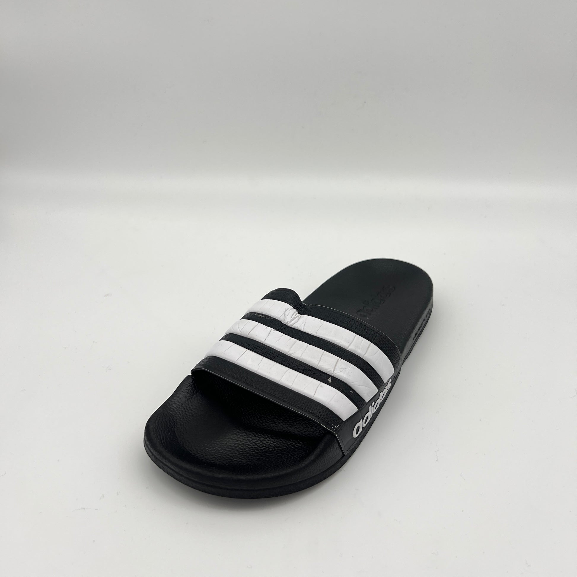 Black slide sandal with white stripes on a light gray background
