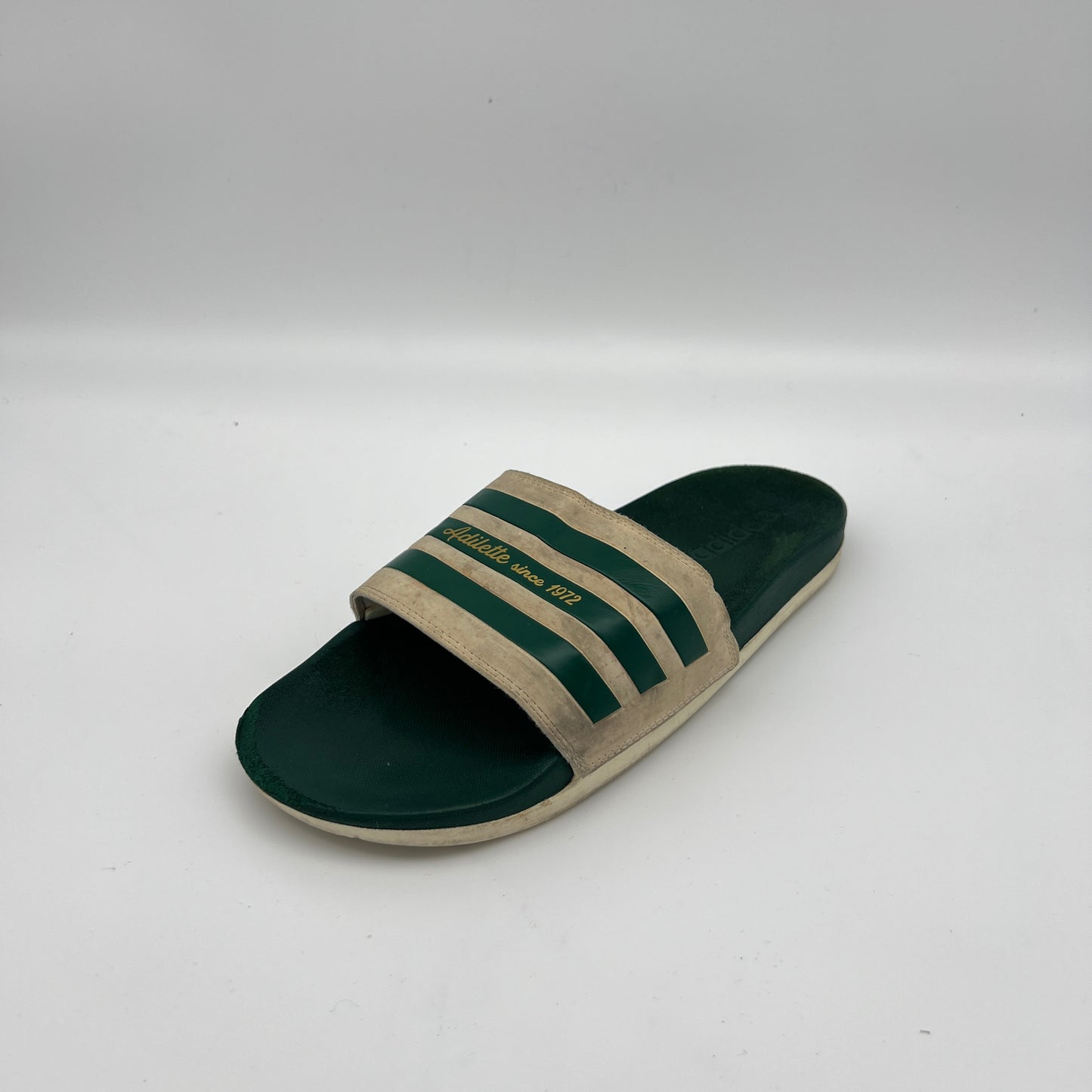 Green and beige slide sandal with three stripes on a white background