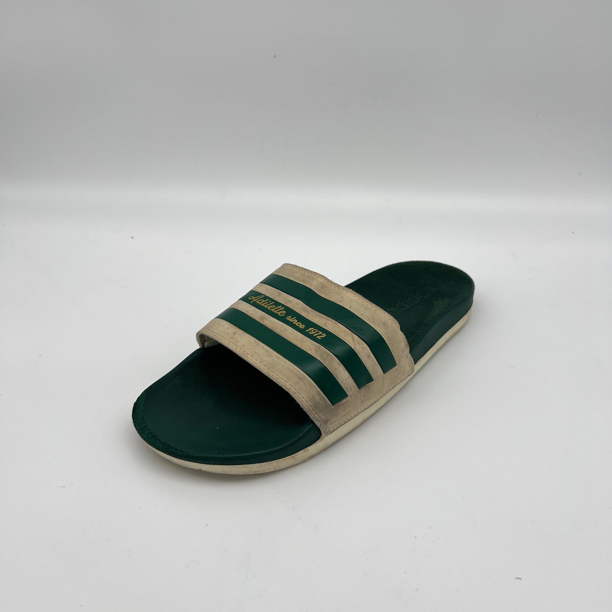 Green and beige slide sandal with three stripes on a white background