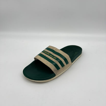 Green and beige slide sandal with three stripes on a white background