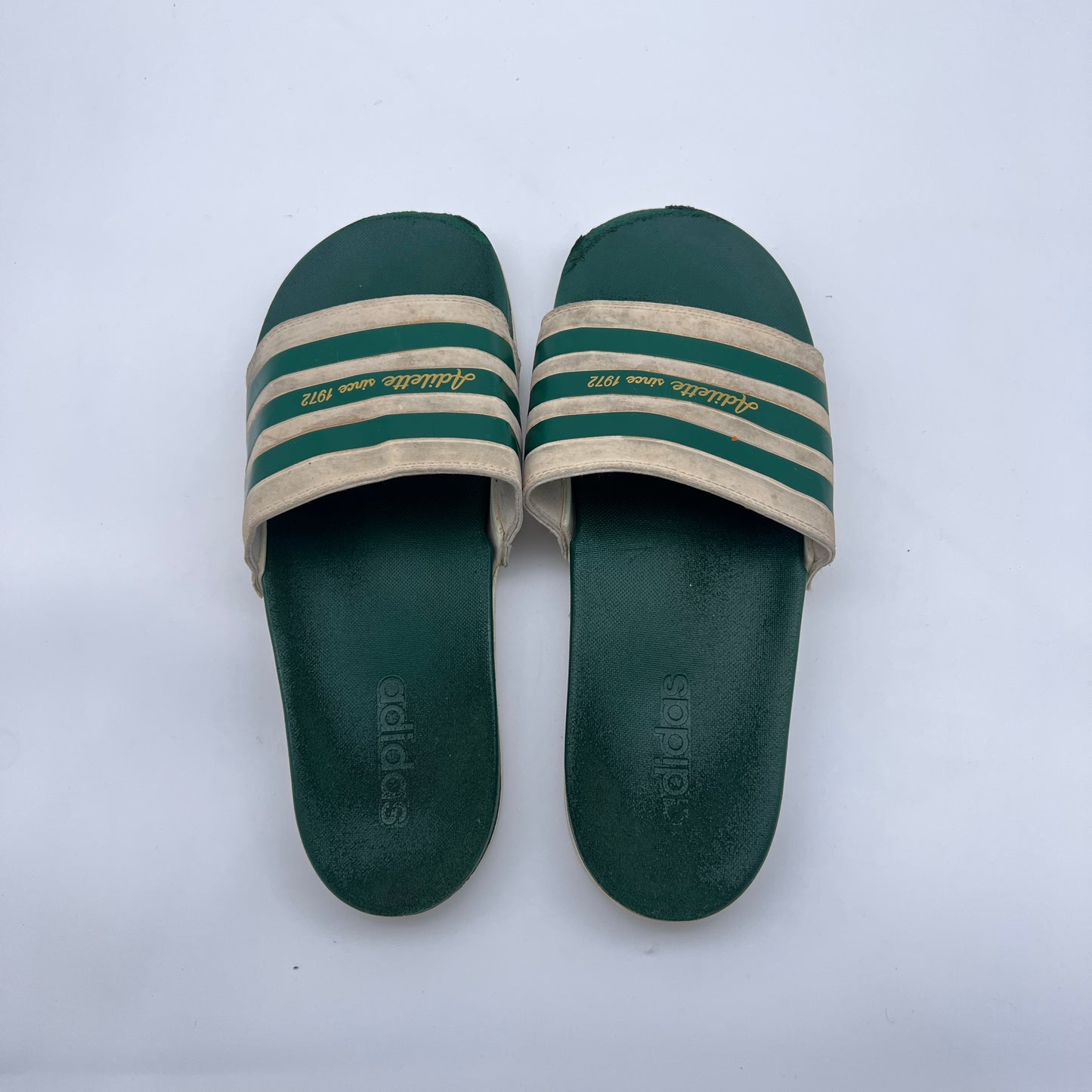 Men's vintage-style Adidas slides; comfortable forest green and cream Adilette sandals with heritage branding and contoured sole.