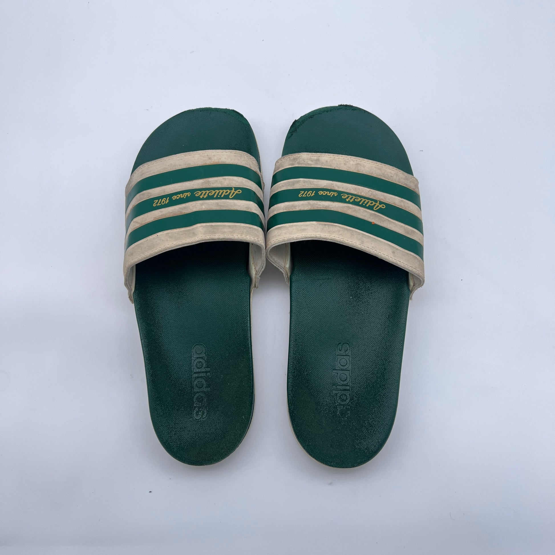 Men's vintage-style Adidas slides; comfortable forest green and cream Adilette sandals with heritage branding and contoured sole.