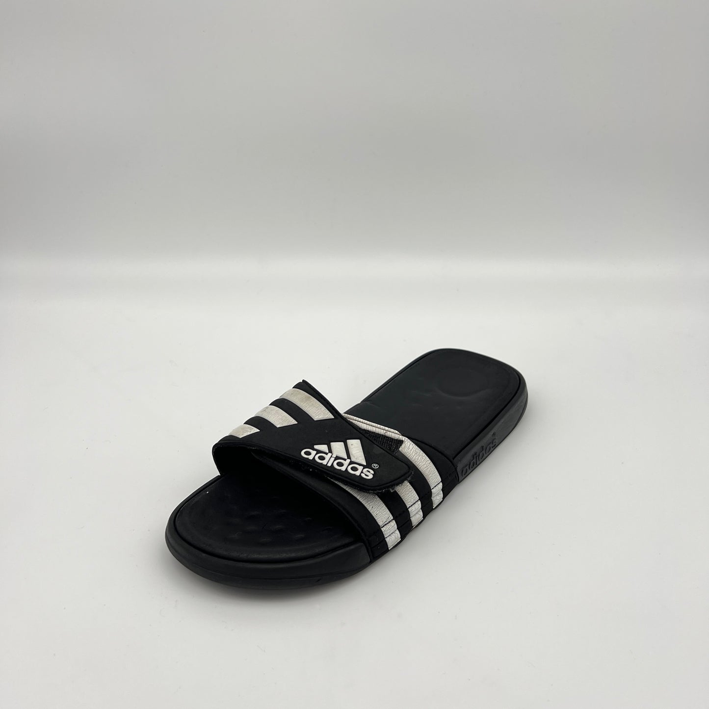 Black Adidas slide sandal on a white background