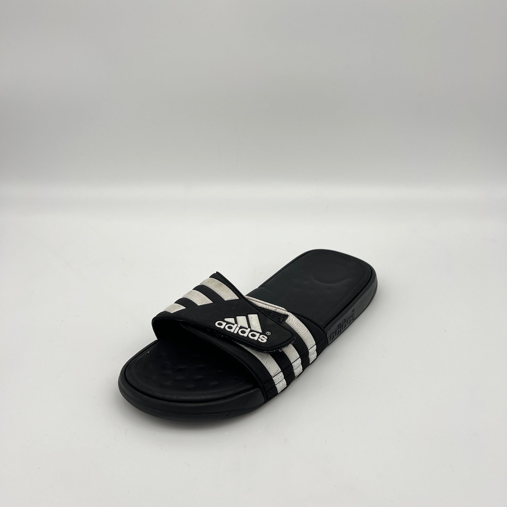 Black Adidas slide sandal on a white background