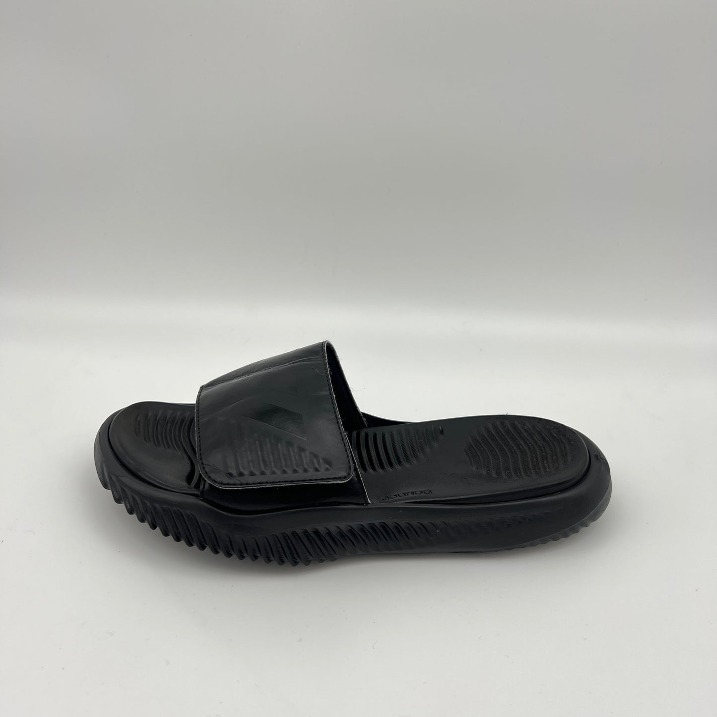 Side view of an all-black Adidas Alphabounce slide sandal on a white background showing the textured footbed and adjustable 3-stripes strap.