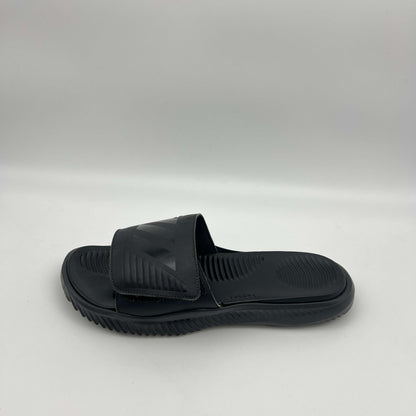 A side profile of an all-black Adidas Alphabounce slide featuring an adjustable strap with debossed branding and a thick, contoured Bounce cushioned sole.