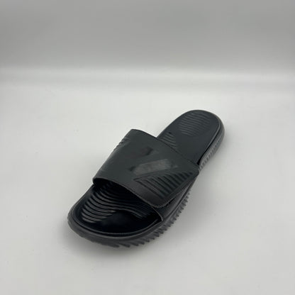 A side profile of an all-black Adidas Alphabounce slide featuring an adjustable strap with debossed branding and a thick, contoured Bounce cushioned sole.