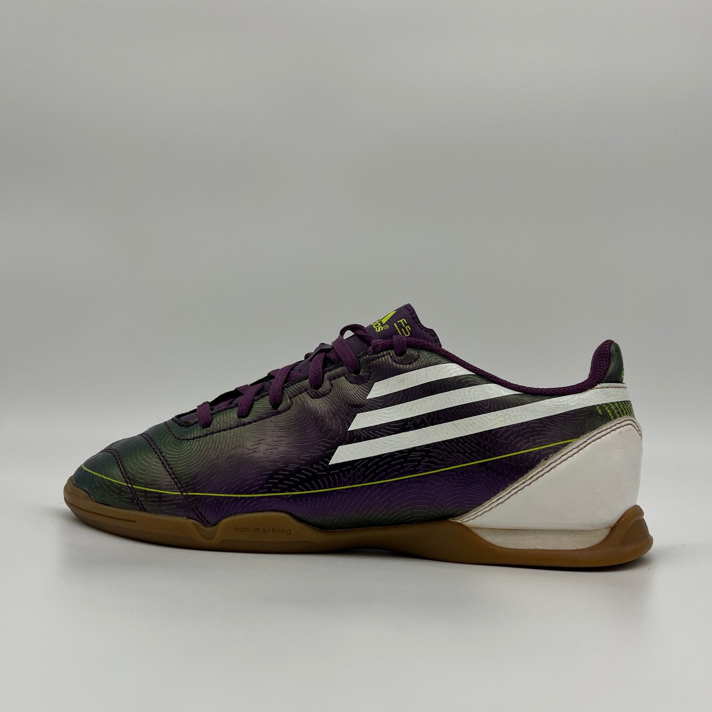 Side profile of a purple Adidas F10 indoor soccer shoe with white stripes and a gum rubber sole
