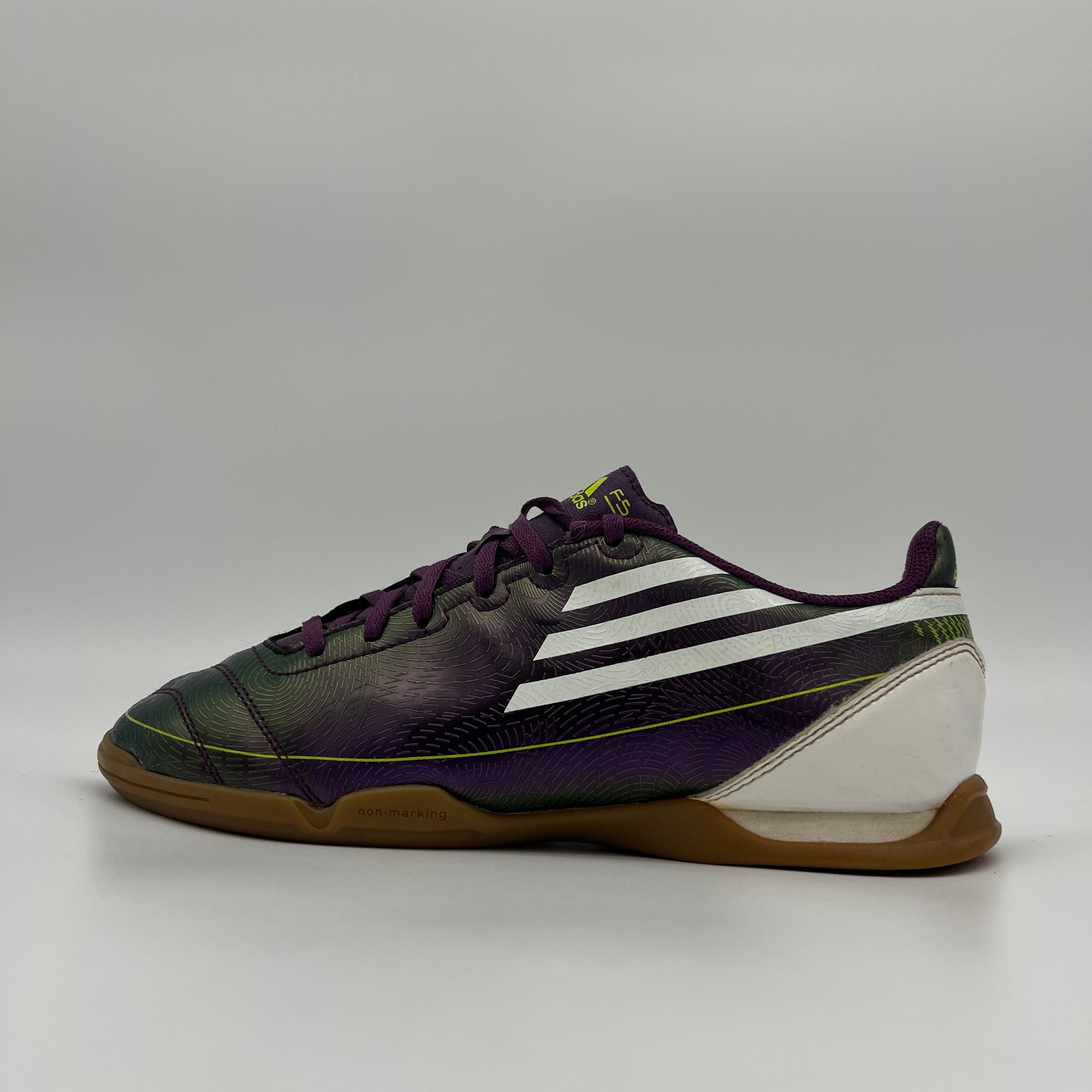 Side profile of a purple Adidas F10 indoor soccer shoe with white stripes and a gum rubber sole