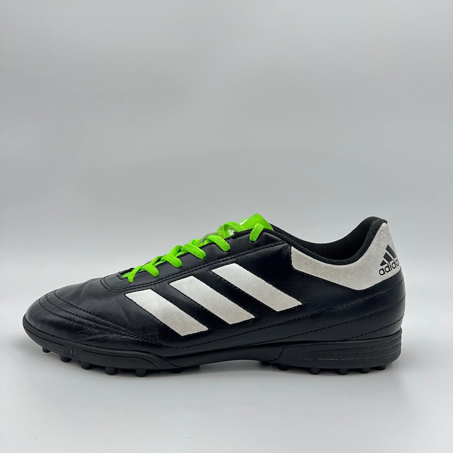 Side view of black Adidas Goletto VI TF soccer shoe with white stripes and green laces