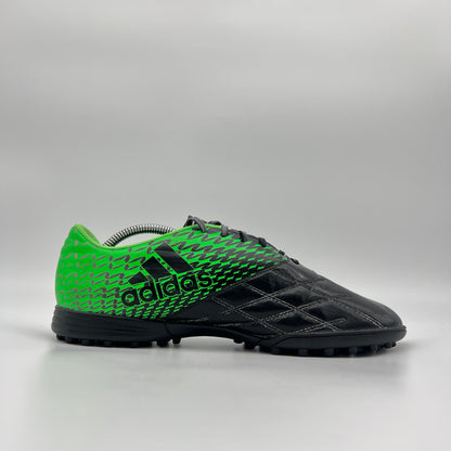 Side profile of a black and neon green Adidas Neoride TRX TF soccer shoe, featuring white stripes and a multi-studded turf outsole