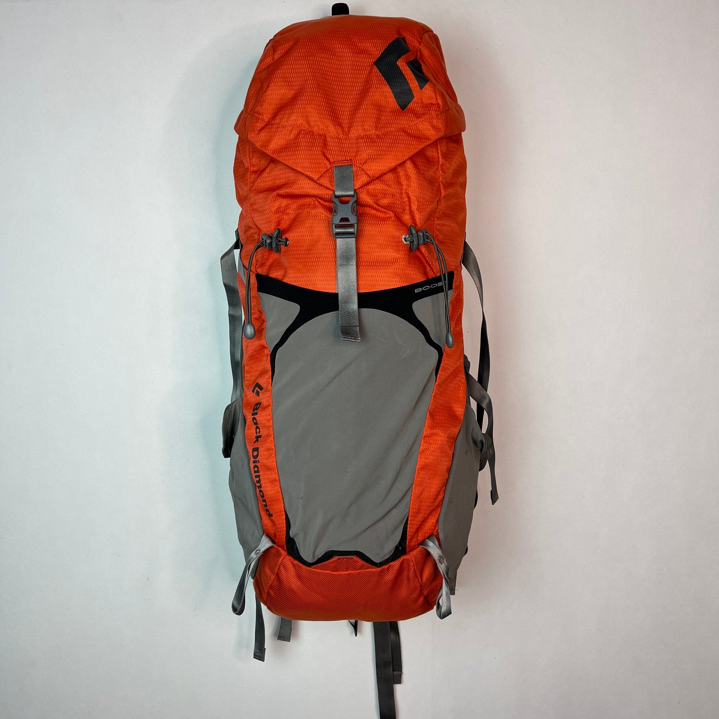Front view of a Black Diamond Axiom 30 liter technical hiking backpack in burnt orange and grey, featuring adjustable compression straps and a spacious lid.