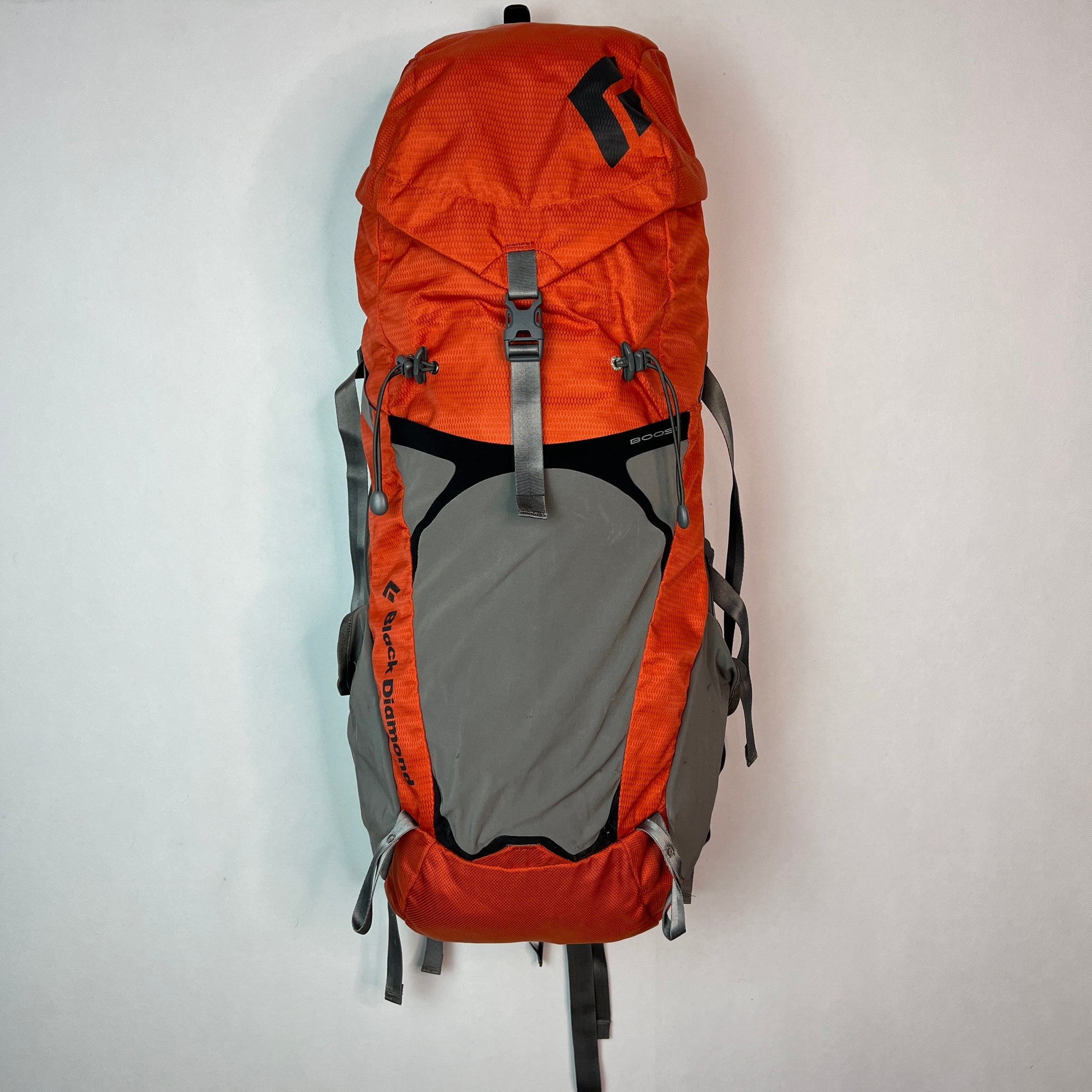 Front view of a Black Diamond Axiom 30 liter technical hiking backpack in burnt orange and grey, featuring adjustable compression straps and a spacious lid.