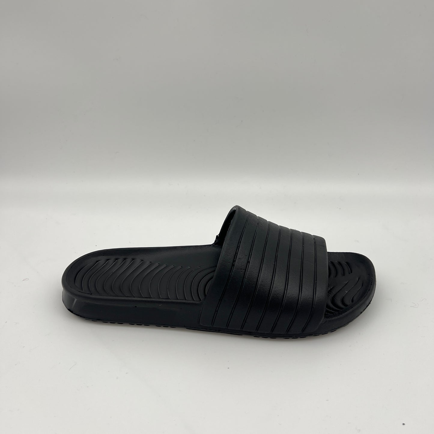 All-black men's tunnel slides with a textured ribbed strap and wave-patterned footbed.