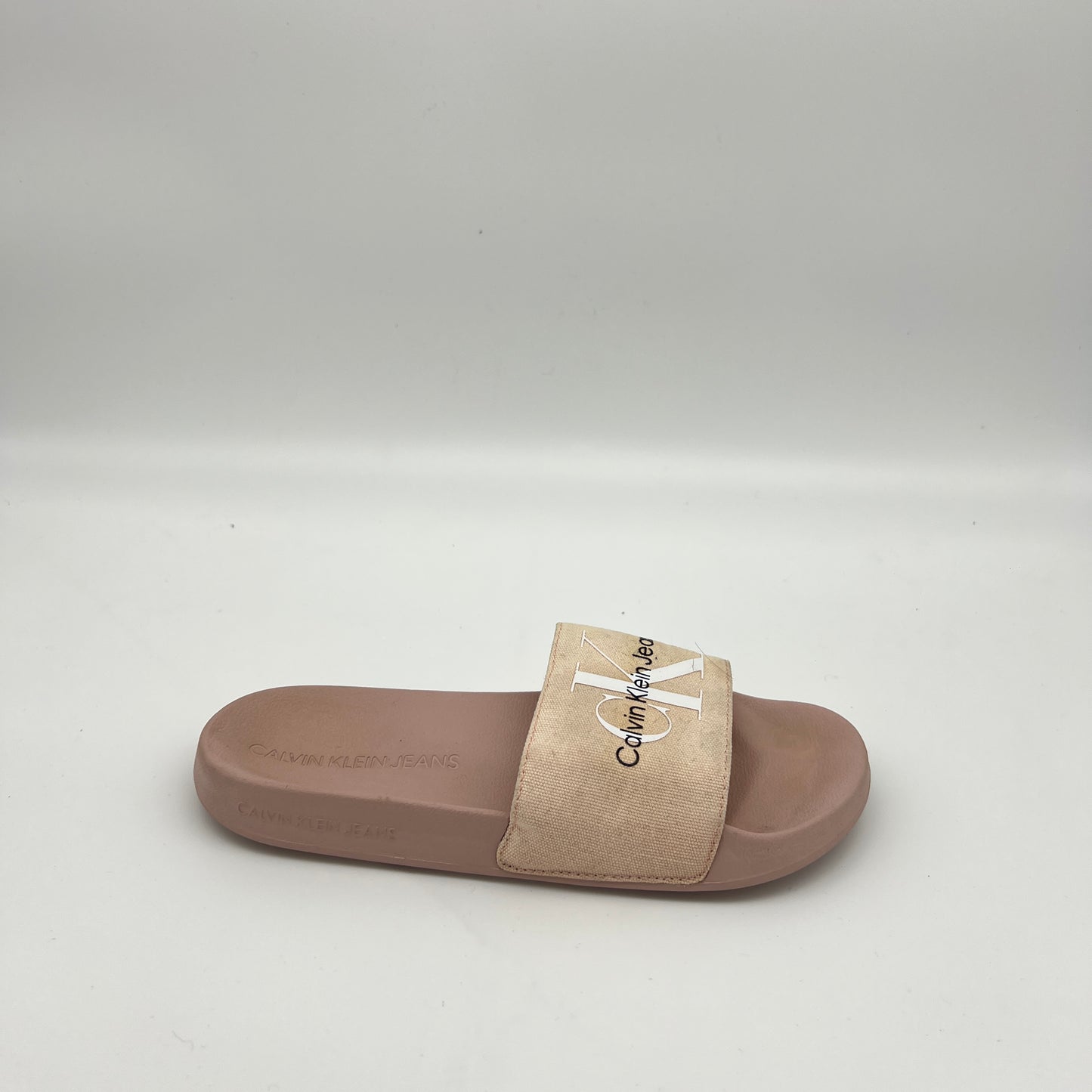 Side view of Calvin Klein Jeans slide sandal in dusty pink and beige with a large monogram logo.