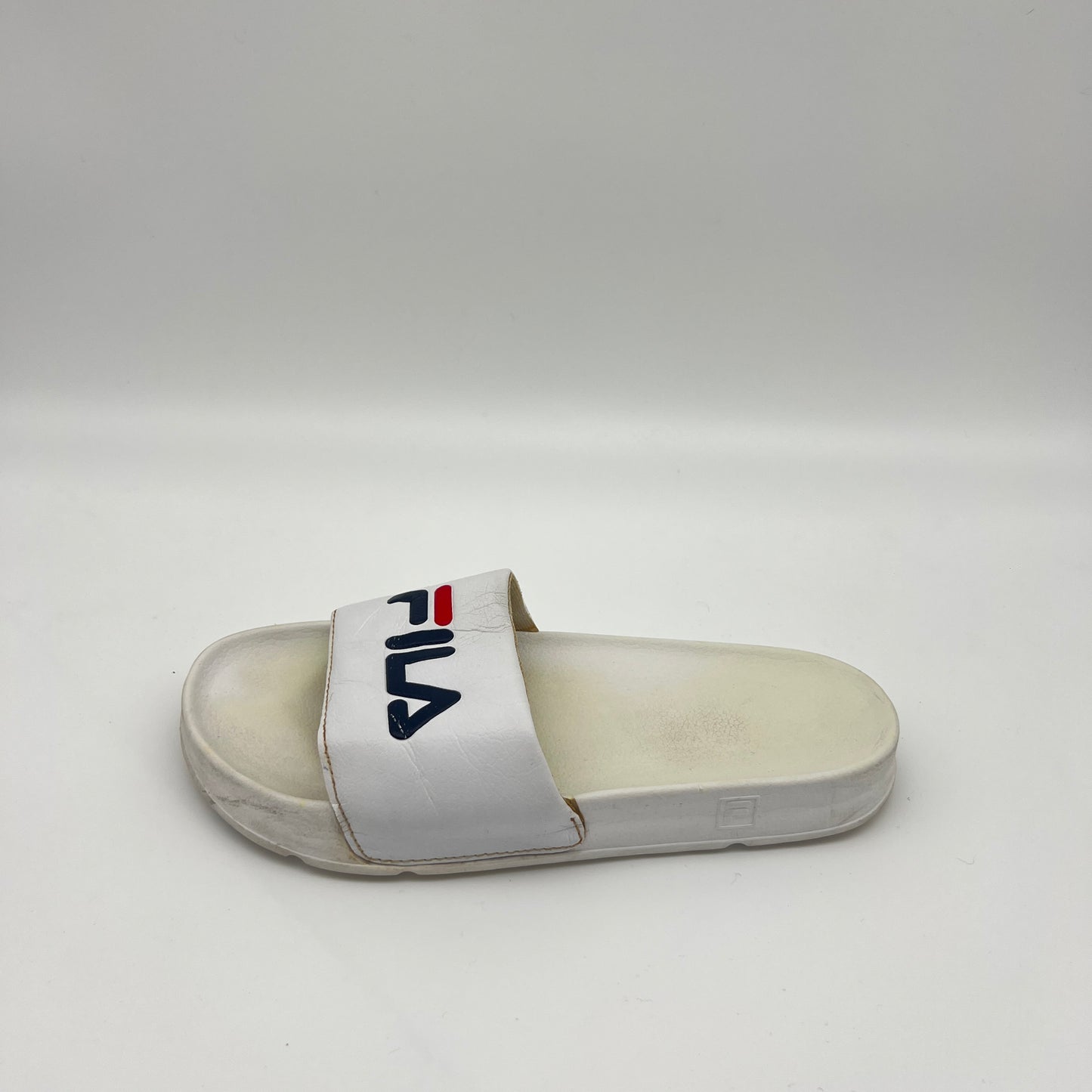 A side view of a white Fila Morro Bay 2.0 slide featuring a navy and red Fila logo on the strap and a thick, contoured sole