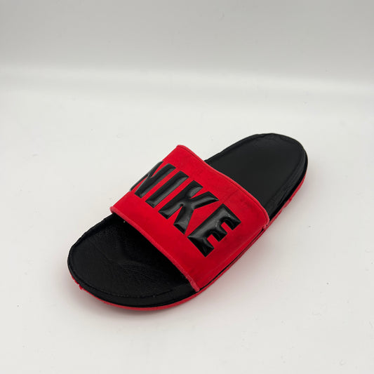 Red and black slide sandal with Nike logo on a white background