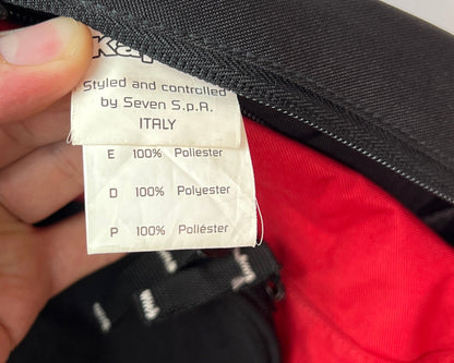 Hand holding a label inside a red and black bag with visible branding.