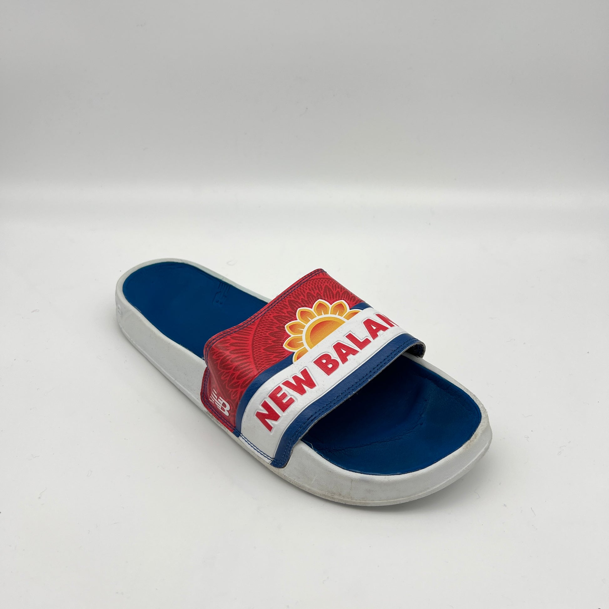 Blue and red slide sandal with New Balance logo on a white background