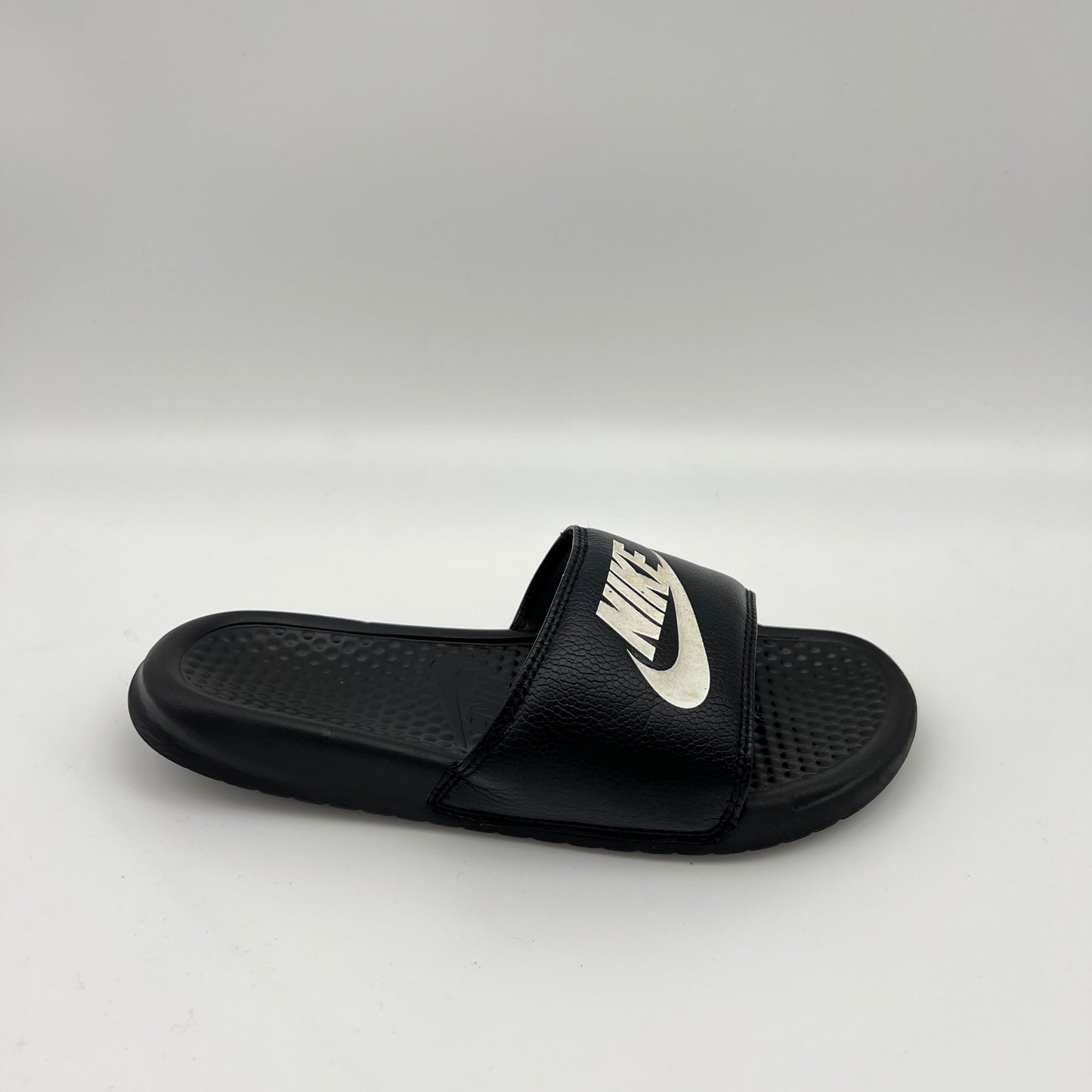 Black slide sandal with Nike logo on a white background