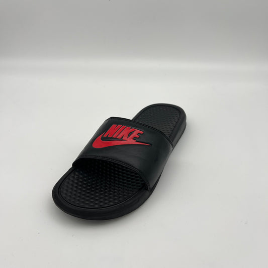 Side view of black Nike Benassi JDI slides featuring a padded synthetic leather strap and massage-textured footbed.