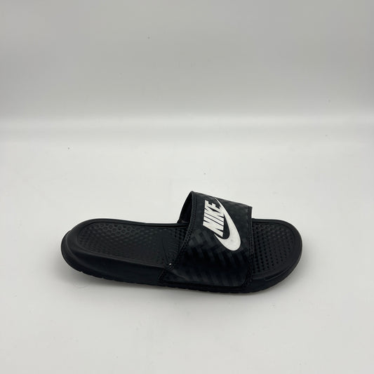Side profile of a black Nike Benassi JDI slide sandal featuring a tonal diamond-grid pattern on the strap and a bold white Nike logo on a white background.