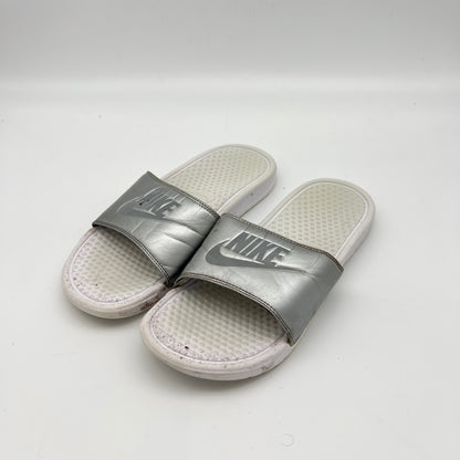 Silver Nike slides on a white background