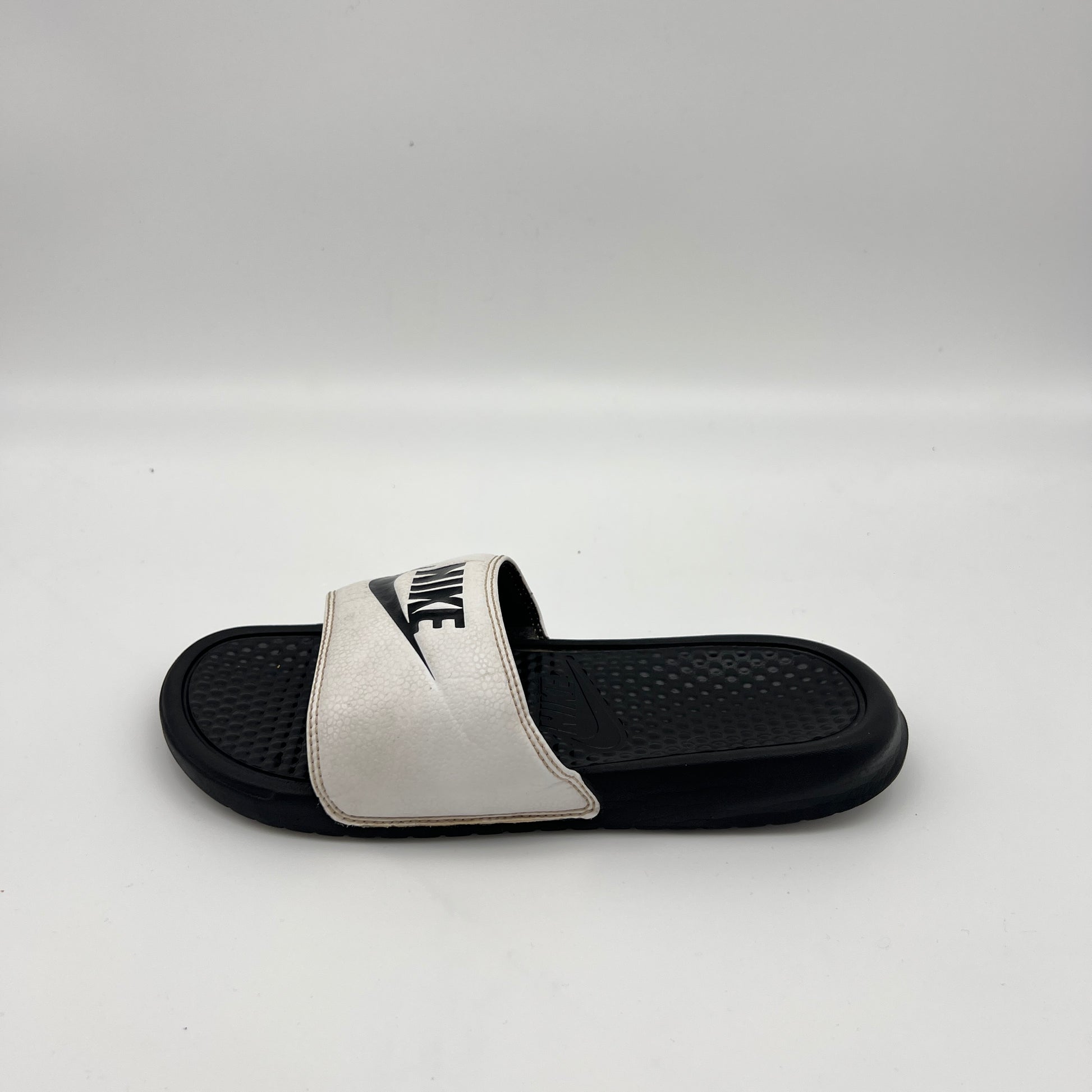 Side view of Nike Benassi JDI slide sandal in white and black with a contoured footbed.