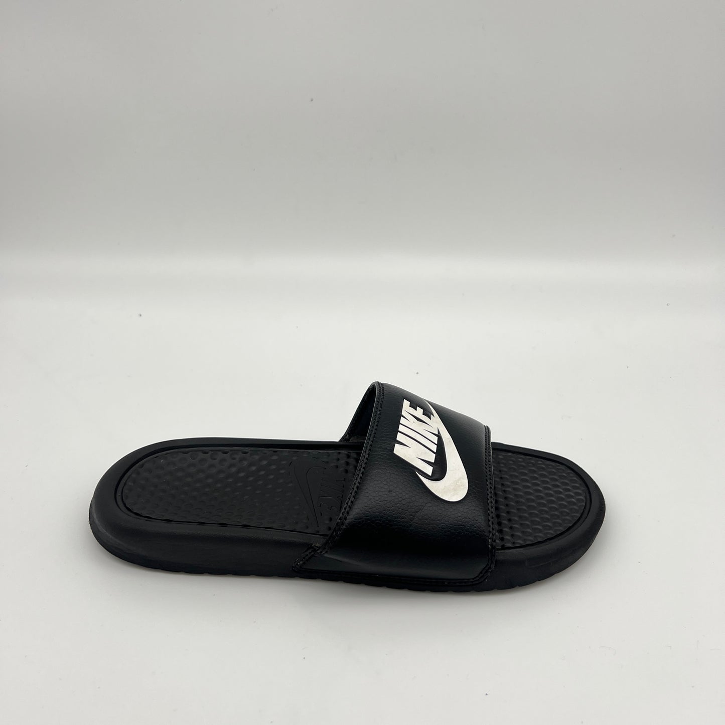 Side view of Nike Benassi JDI slide sandal in black and white with a textured footbed