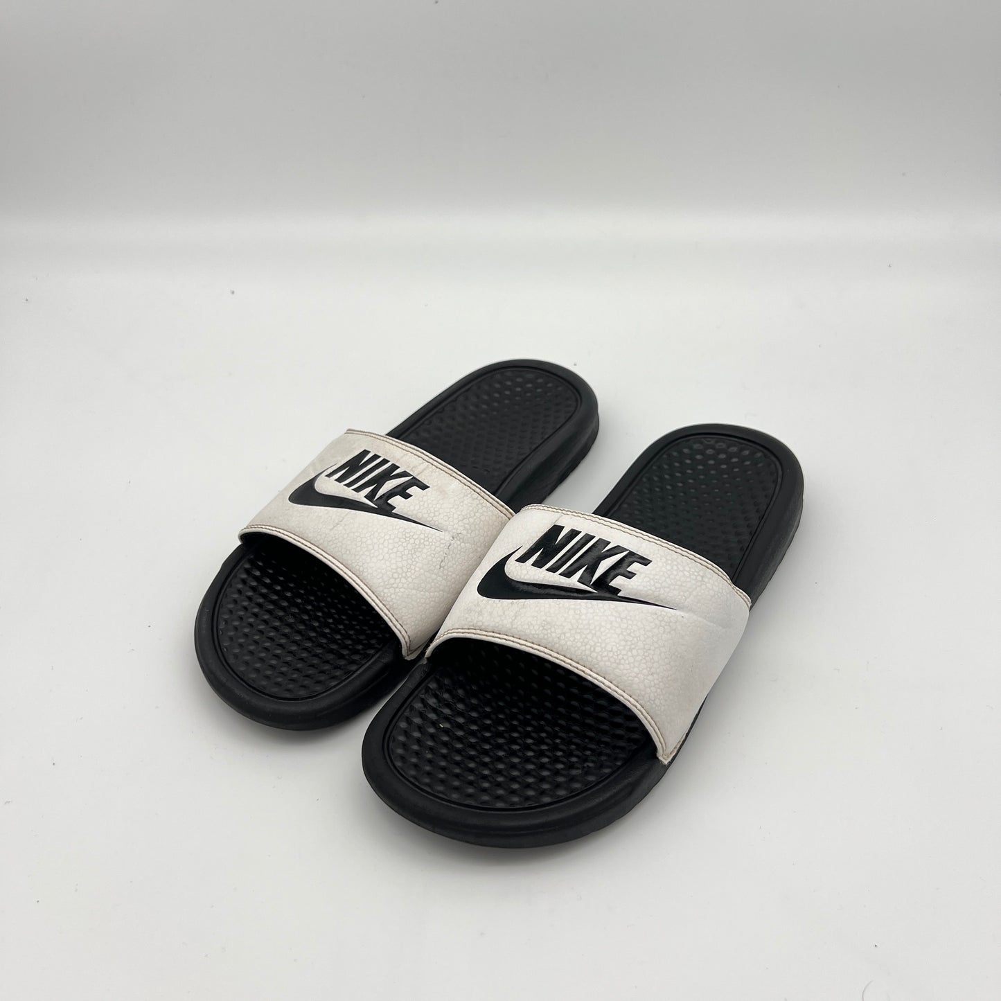Lightweight Nike Benassi sandals with a cushioned footbed for post-workout recovery.