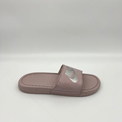 Side view of a mauve Nike Benassi JDI slide sandal featuring a metallic silver Nike logo on the strap and a textured Solarsoft foam footbed.