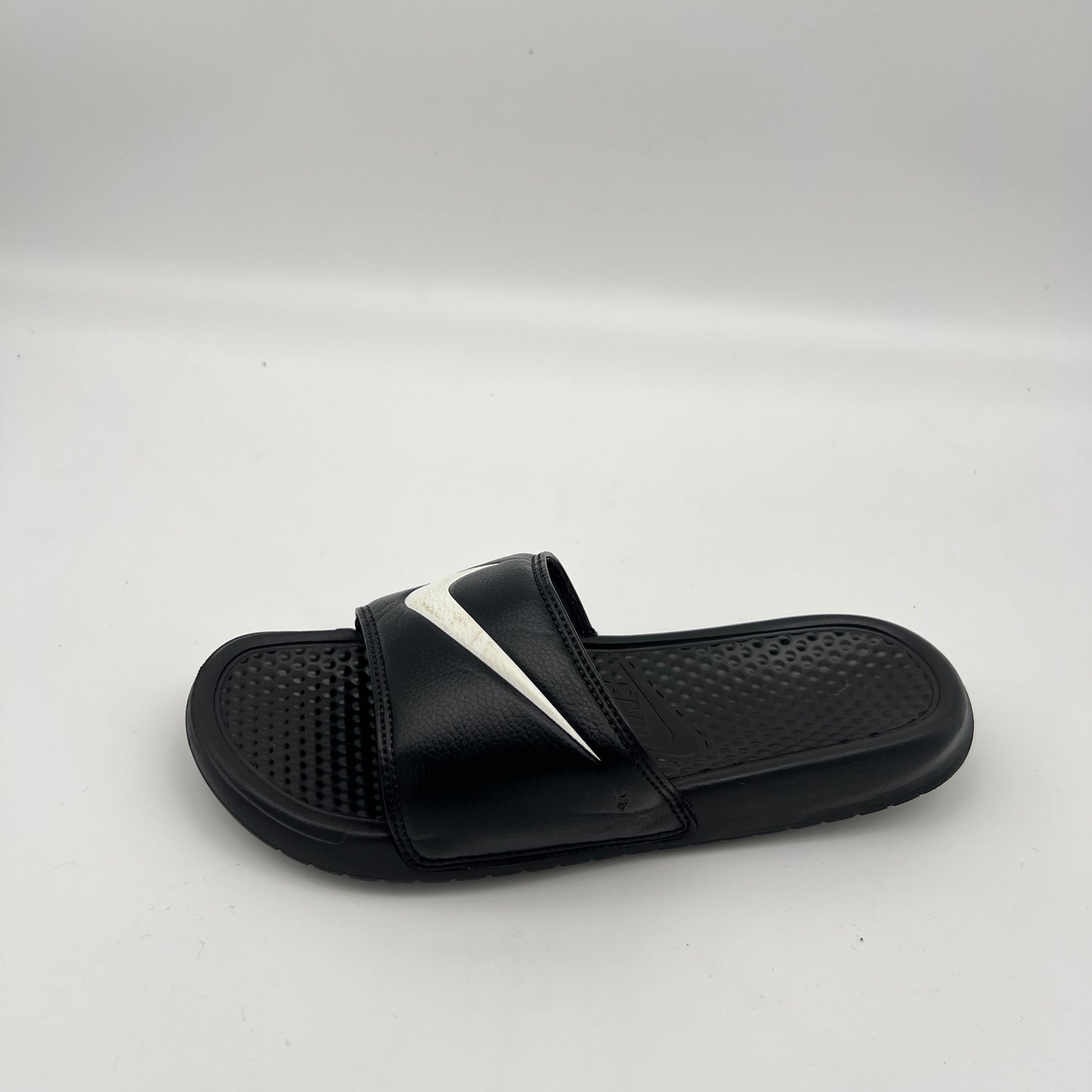 Black Nike Benassi JDI slide sandal with a white swoosh logo and textured footbed.