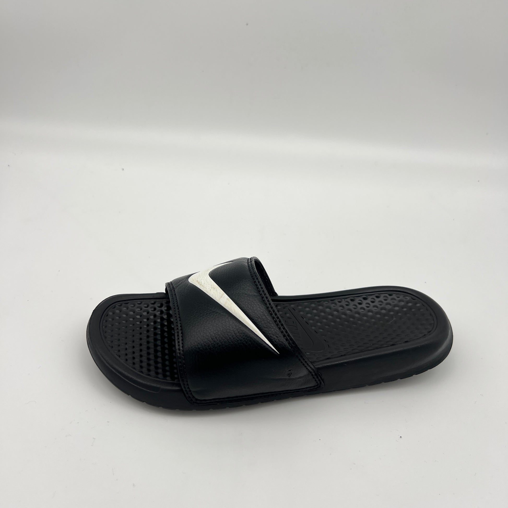 Black Nike Benassi JDI slide sandal with a white swoosh logo and textured footbed.