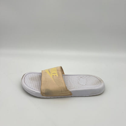 Side view of a pale ivory Nike Benassi JDI slide featuring a yellow Nike logo on the padded strap and a textured white Phylon footbed on a white background.