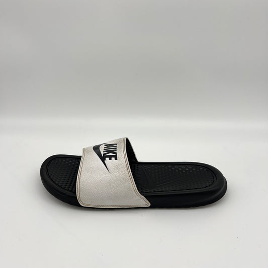 Side view of a Nike Benassi JDI slide with a white pebbled-texture strap and black Nike logo, featuring a textured black footbed on a clean white background.
